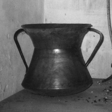 An copper pot with two handles on either side